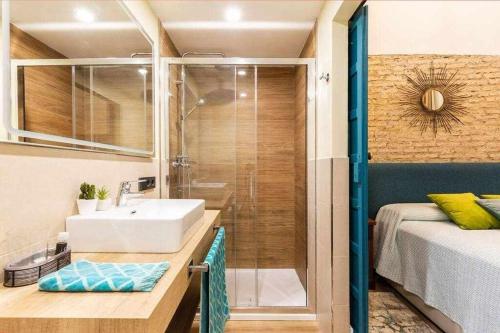 baño con lavabo y ducha junto a una cama en MonKeys Apartments Betis Chill Out, en Sevilla