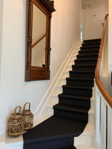 a stairway with a mirror and a black rug at Hotel Egeskoven in Viborg