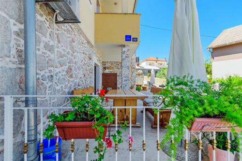 a balcony with potted plants and a table at Stone house on the Batalaža Beach - Kali in Kali