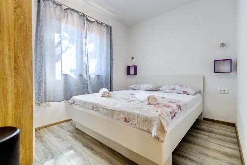 a white bedroom with a bed with a window at Stone house on the Batalaža Beach - Kali in Kali