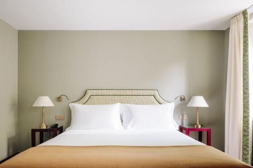 a bedroom with a large white bed with two lamps at Hotel das Amoreiras - Small Luxury Hotels of the World in Lisbon