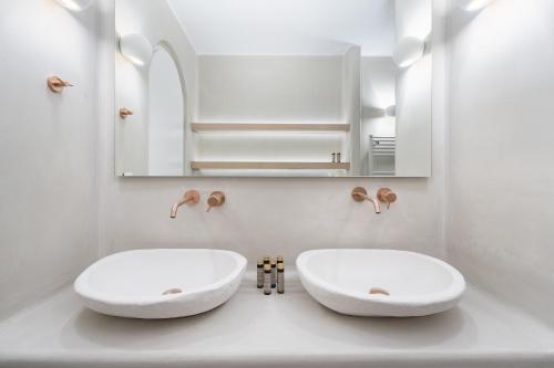 a bathroom with two white sinks and a mirror at Airth Santorini Suites in Firostefani