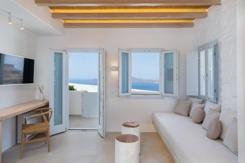Biały salon z białą kanapą i oknami w obiekcie Airth Santorini Suites w mieście Firostefani