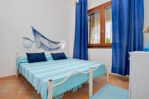 a bedroom with a bed with blue curtains and a window at Il Giardino di Viola in Porto Ottiolu