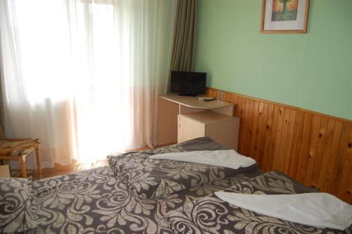 a hotel room with two beds and a television at Хотел Варненци in Lŭki