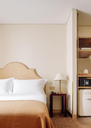 a bedroom with a bed and a table with a lamp at Hotel das Amoreiras - Small Luxury Hotels of the World in Lisbon