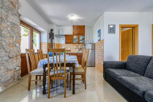 a dining room and kitchen with a table and a couch at Stone house on the Batalaža Beach - Kali in Kali