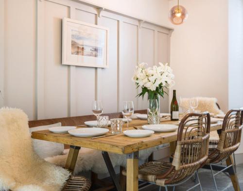 a wooden table with chairs and a vase of flowers at Albany in Port Isaac