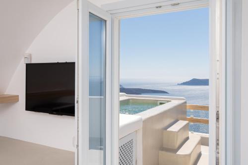 a balcony with a television and a swimming pool at Airth Santorini Suites in Firostefani