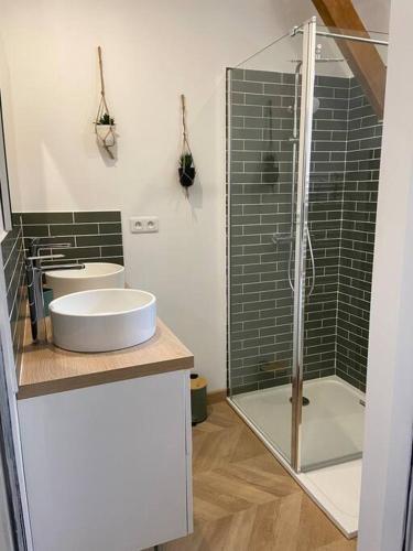 a bathroom with two sinks and a glass shower at La Charmeraie : Le Logis in Thésée