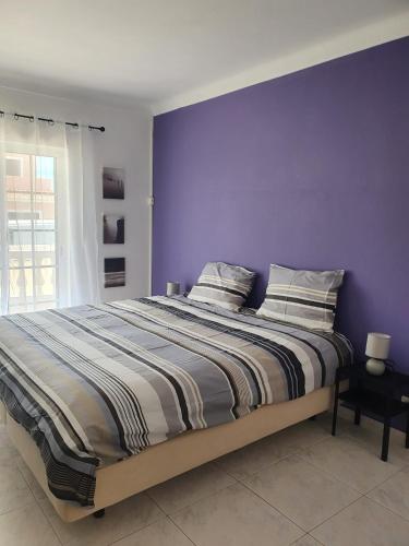a bedroom with a bed with a purple wall at Brisa's Haven Guesthouse !Pet Friendly! in Lagos