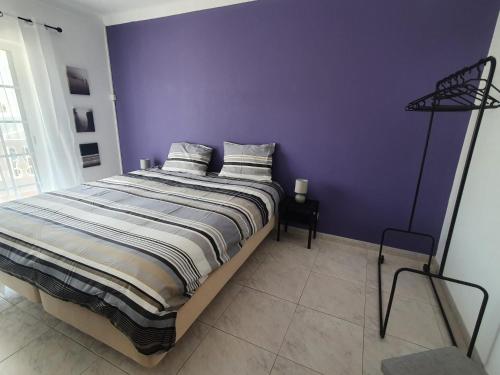 a bedroom with a bed with a purple wall at Brisa's Haven Guesthouse !Pet Friendly! in Lagos