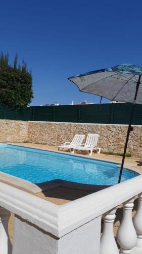 a pool with two chairs and an umbrella at Brisa's Haven Guesthouse !Pet Friendly! in Lagos