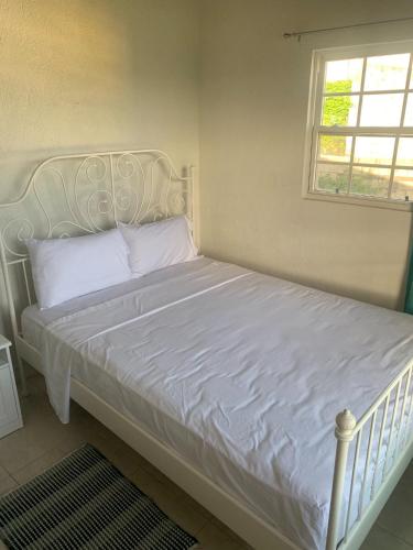 - un lit blanc dans une chambre avec fenêtre dans l'établissement Pine Breeze Apartments, à Bridgetown