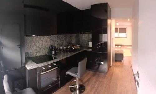 a kitchen with black cabinets and a wooden floor at New Apartment Apartament modern recent construit Modern újépítésű társasházi lakrész in Miercurea-Ciuc