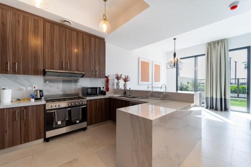 a kitchen with wooden cabinets and a stainless steel stove at Marbella Luxury 3BR & 5BR Villas at Hayat Island, Mina Al Arab in Ras al Khaimah