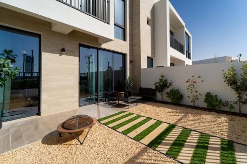 a house with a grassy courtyard in front of it at Marbella Luxury 3BR & 5BR Villas at Hayat Island, Mina Al Arab in Ras al Khaimah