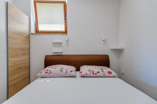 a bed in a room with two pillows on it at Stone house on the Batalaža Beach - Kali in Kali