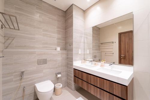 a bathroom with a sink and a toilet and a mirror at Marbella Luxury 3BR & 5BR Villas at Hayat Island, Mina Al Arab in Ras al Khaimah