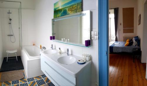 a white bathroom with a sink and a mirror at La maison des dentelliers in Calais