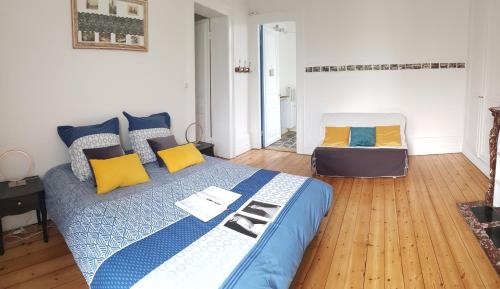a bedroom with a bed with blue and yellow pillows at La maison des dentelliers in Calais