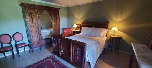 1 Schlafzimmer mit einem Bett, 2 Stühlen und einem Spiegel in der Unterkunft Casas da Tapada Briteiros Casa das Cortes in Guimarães