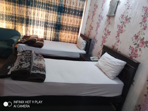 two twin beds in a room with a window at HOTEL DE GRAND in Rawalpindi
