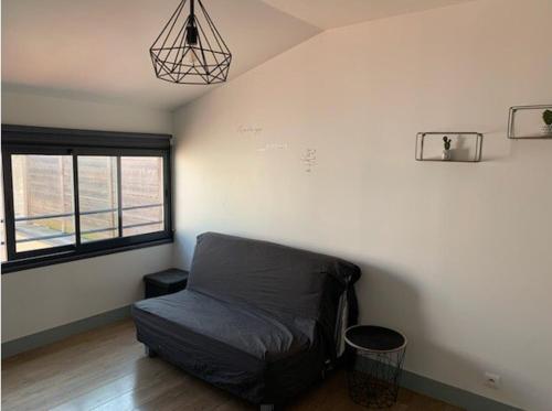 ein Zimmer mit einem Bett in einem Zimmer mit einem Fenster in der Unterkunft Studio centre historique de La Rochelle in La Rochelle