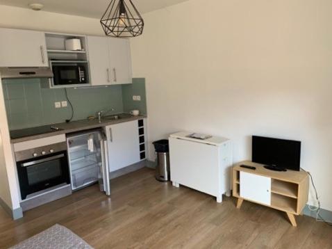 eine Küche mit weißen Schränken und einem TV in der Unterkunft Studio centre historique de La Rochelle in La Rochelle