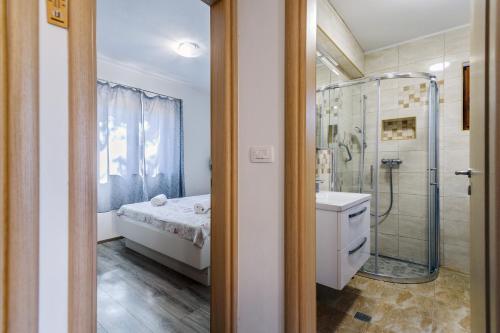 baño con ducha, cama y lavamanos en Stone house on the Batalaža Beach - Kali en Kali