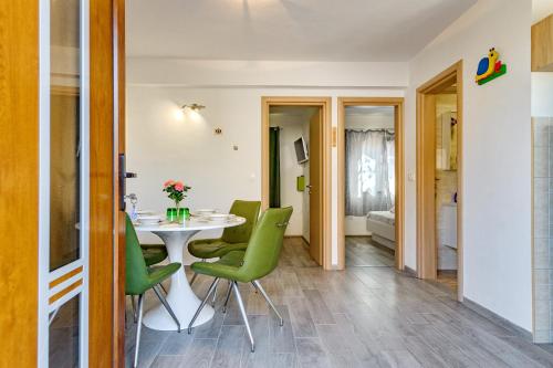 a dining room with a table and green chairs at Stone house on the Batalaža Beach - Kali in Kali