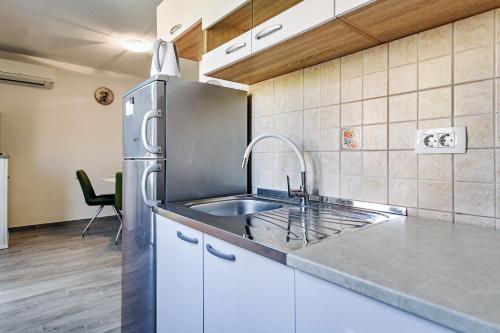 a kitchen with a sink and a stainless steel refrigerator at Stone house on the Batalaža Beach - Kali in Kali