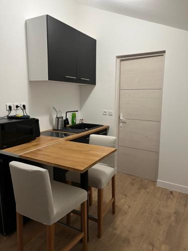 une cuisine avec une table en bois et quelques chaises dans l'établissement Studio avec terrasse Paris Sud, à Villejuif