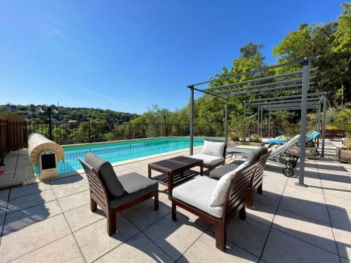 um pátio com uma mesa e cadeiras ao lado de uma piscina em Gîtes Le Bouzet em Salavas