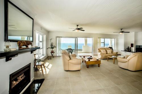 a living room with two chairs and a fireplace at Penguinden - load-shedding free in Simonʼs Town