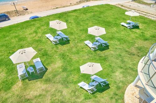 un gruppo di sedie e ombrelloni su un prato di Armikes Beachfront Suites Afionas a Afionas
