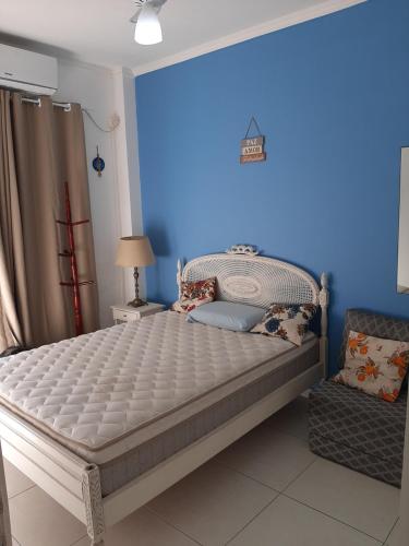 a bed in a room with a blue wall at Apartamento Vento e mar - 2 quartos com sacada na quadra da praia com sauna a vapor in Santos