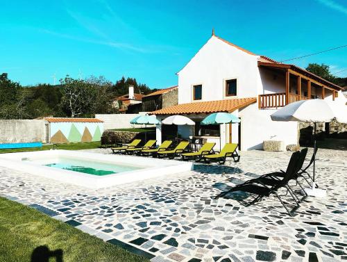 a house with a swimming pool with chairs and umbrellas at NocasHouse Lousa in Fojo