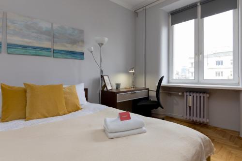 a bedroom with a white bed with a red cross on it at Grójecka Stara Ochota Apartment in Warsaw