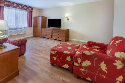 a living room with a red couch and a tv at Baymont by Wyndham Perrysburg-Toledo in Perrysburg