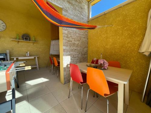 a dining room with a table and orange chairs at Gîtes Le Bouzet in Salavas