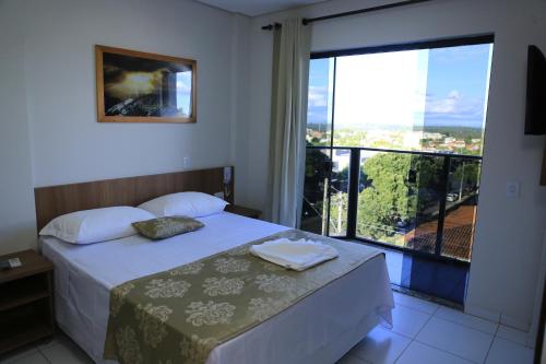 a bedroom with a bed and a large window at Pontal Executive Hotel in Curvelo