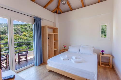 a bedroom with a white bed and a balcony at Toni Retzo Rooms in Himare