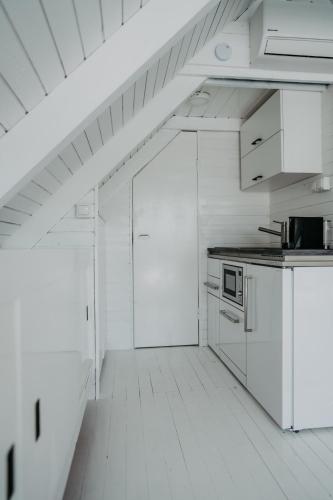 a kitchen with white cabinets and a white floor at Seehütte Neusiedlersee - Strandhaus, Elektroboot inklusive in Rust