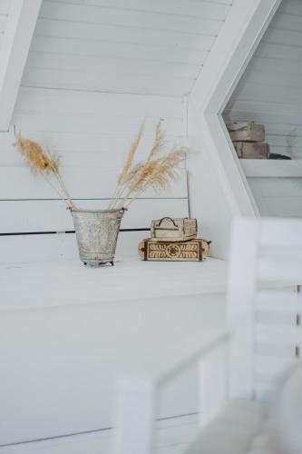 a white room with a vase and books on a shelf at Seehütte Neusiedlersee - Strandhaus, Elektroboot inklusive in Rust