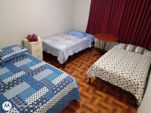 um quarto com duas camas e uma mesa em Hostal Kmr em Chosica