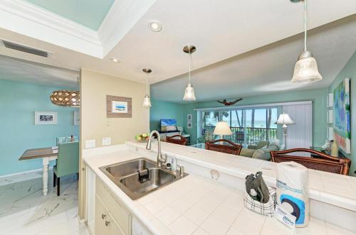 a kitchen with a sink and a living room at Sunset Beach 102: Gulf Front, Stunning Views, On the Beach, Pool by Anna Maria Life Vacation Rentals in Holmes Beach