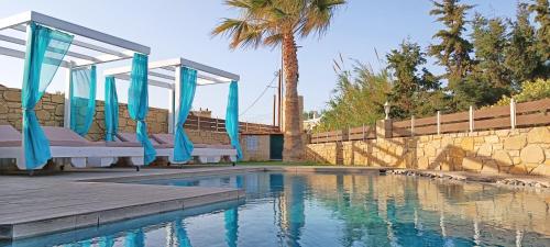 a swimming pool with blue umbrellas in front of a building at Elena Villa in Kissamos