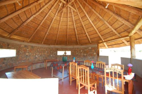 jadalnia z drewnianymi stołami i krzesłami w budynku w obiekcie MARK's farm & ecolodge w mieście Kalenga