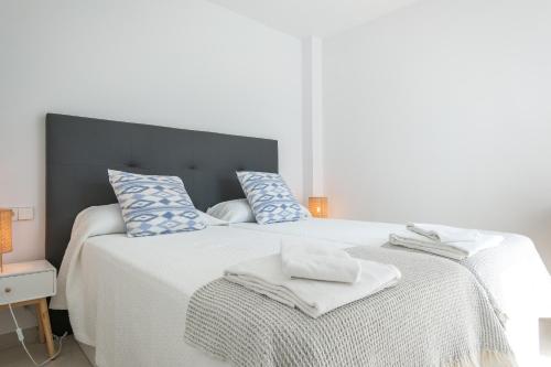 um quarto com uma grande cama branca com almofadas azuis em Sea apartment 1C with pool , 150 meters Canyamel Beach em Capdepera